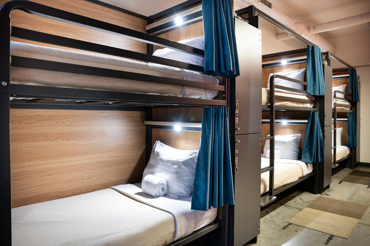 a 6-bed dormitory room at HI Boston hostel with privacy curtains and reading lights on each freshly made bunk bed