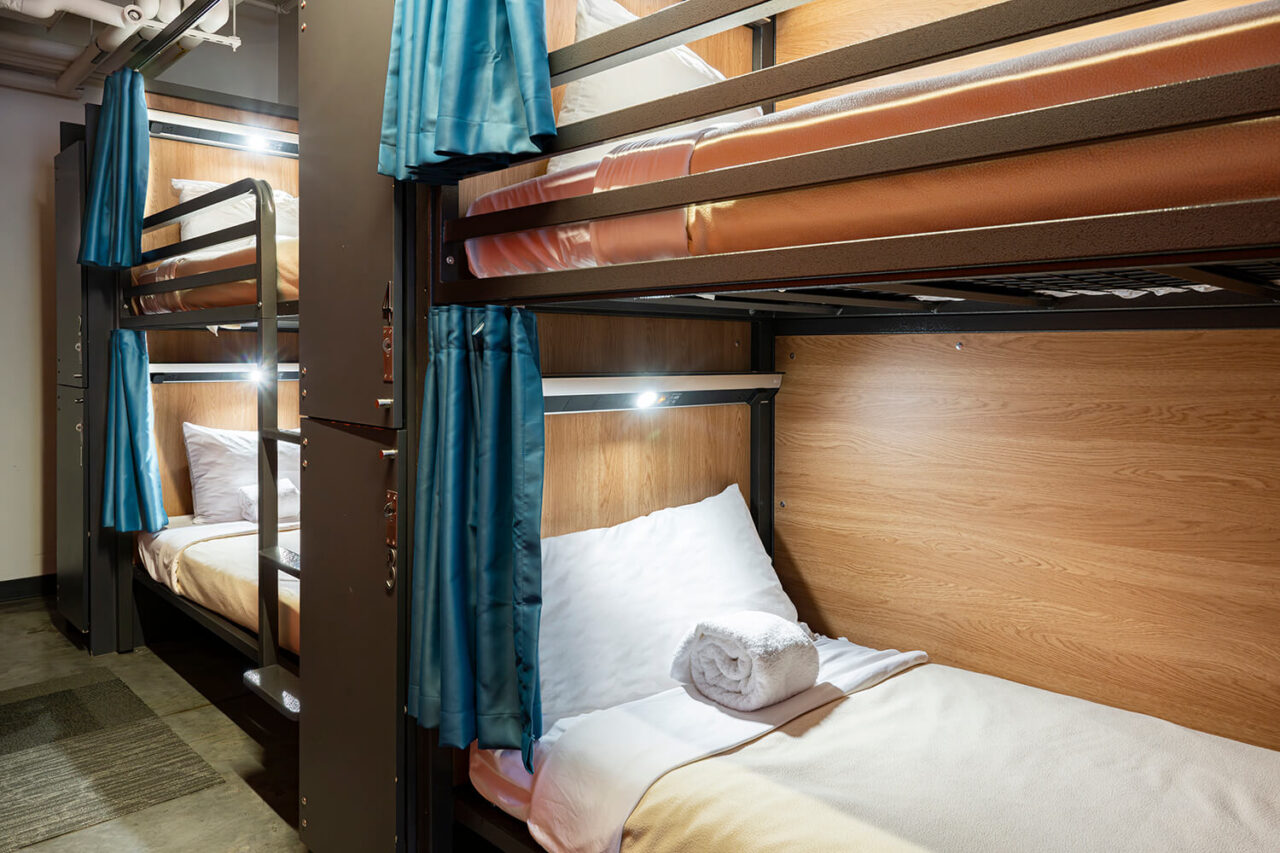 a four-bed dormitory room at HI Boston with privacy curtains and reading lights on each bunk