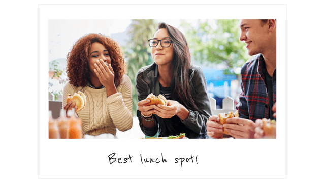 a polaroid photo of three friends eating hamburgers and laughing at a table outside.