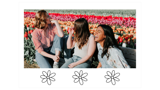 three women sit on a bench laughing in the middle of a fields of colorful tulips