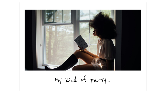 a woman sits in a a window reading a book